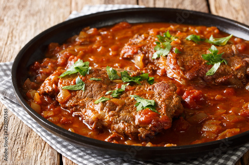 Juicy cube Swiss steak fried and slowly stewed in a spicy tomato sauce with vegetables close-up. horizontal