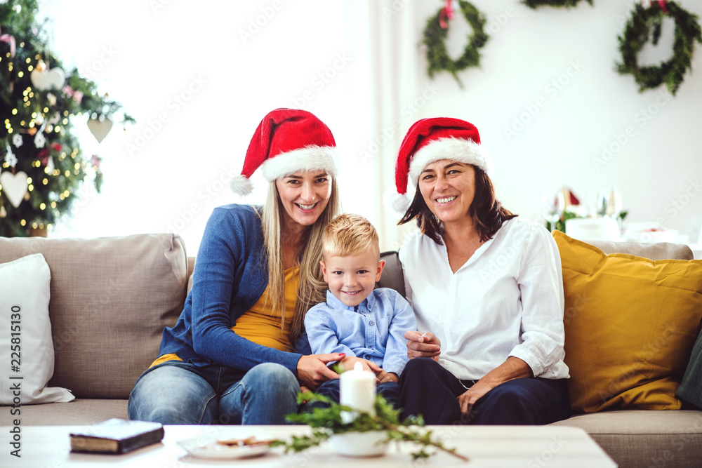 A small boy with mother and grandmother with Santa hat at home at Christmas time. A small boy with mother and grandmother with Santa hat at home at Christmas time.