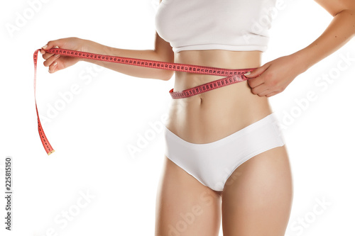 Young woman measure her waist with tape on white background