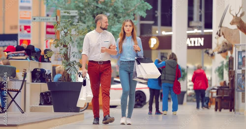 Young beautiful couple in the mall stops near the shop window