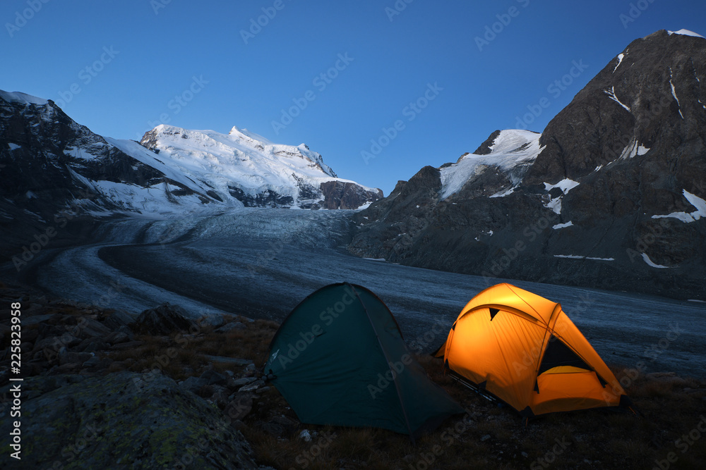 Tenda illuminata all'alba  accanto al ghiacciaio del Grand Comin