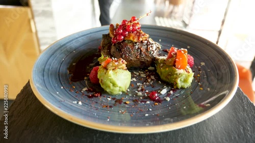 Plate with delicious and juicy grilled beef steak served on a plate to the clients. FPV, POV and waiter point of view. Perfect for your restaurant or food commercial