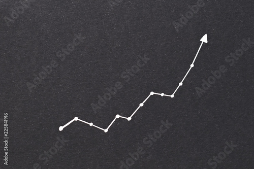 exponential diagram. trend success increase and financial forecast concept. arrow pointing upward on black paper background. photo