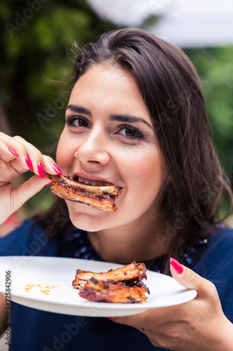 Happy woman eating grilled pork ribs.
