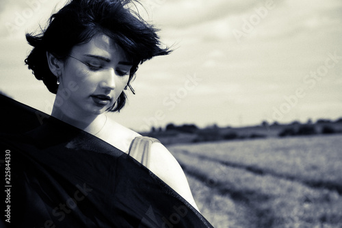 Beautiful stylish female in black and white classical portrait in field