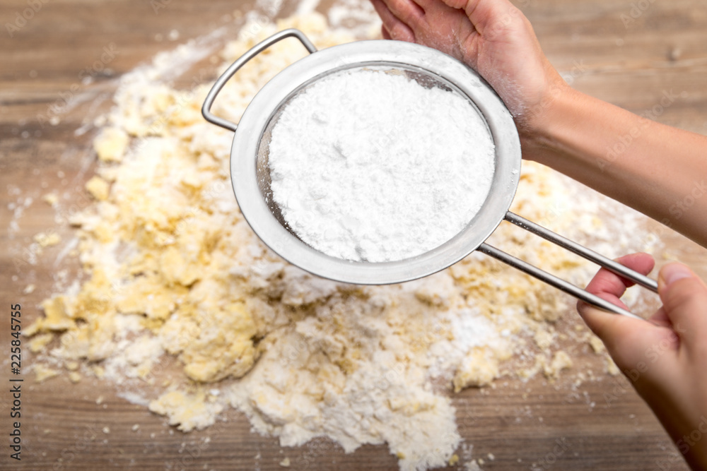 Frau beim durchsieben von Puderzucker auf einen Kuchenteig oder Plätzchenteig Stock Photo