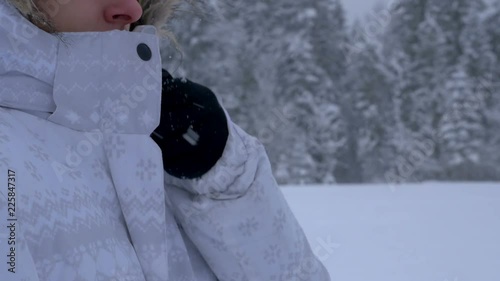 Young woman zipping up a jacket and walking away in winter at a light snowing