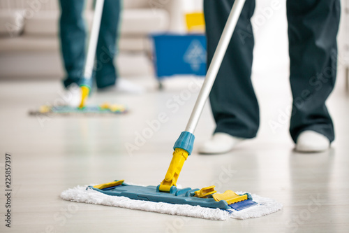 Close-up on mop on the floor holding by cleaning specialist while purifying interior