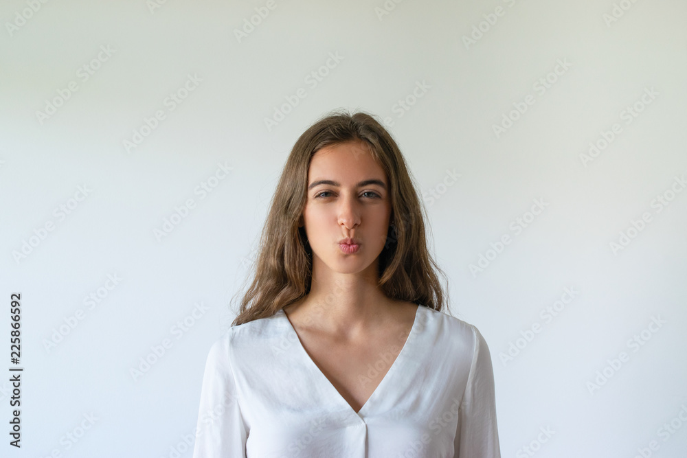 Cheerful girl expressing love emotionally. Female student having fun and posing with kissing face. Romance or fooling concept Cheerful girl expressing love emotionally. Female student having fun and posing with kissing face. Romance or fooling concept