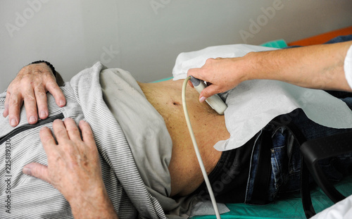 Doctor is using ultrasound machine to scan internal organs of a senior male patient