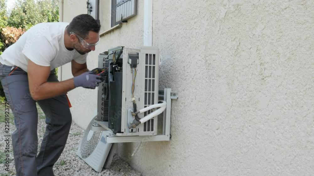 handsome young man electrician installing air conditioning in a client house
