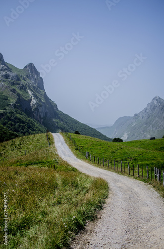 long and lonely path in a green valley between great mountains in somiedo, asturias, spain, europe