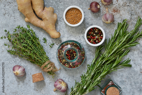 Mix of spices: rosemary, thyme, pepper, garlic, ginger, lemon on a concrete background. Top view. photo