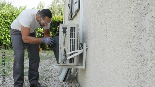 handsome young man electrician installing air conditioning in a client house
