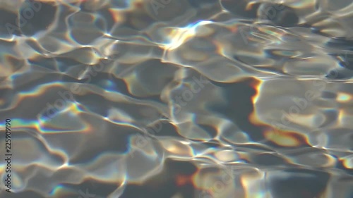 Play of iridescent light on waving gray water surface. Slow motion of abstract rainbow background with fluent ripple close up. Natural pavonine pattern with grid structure.
