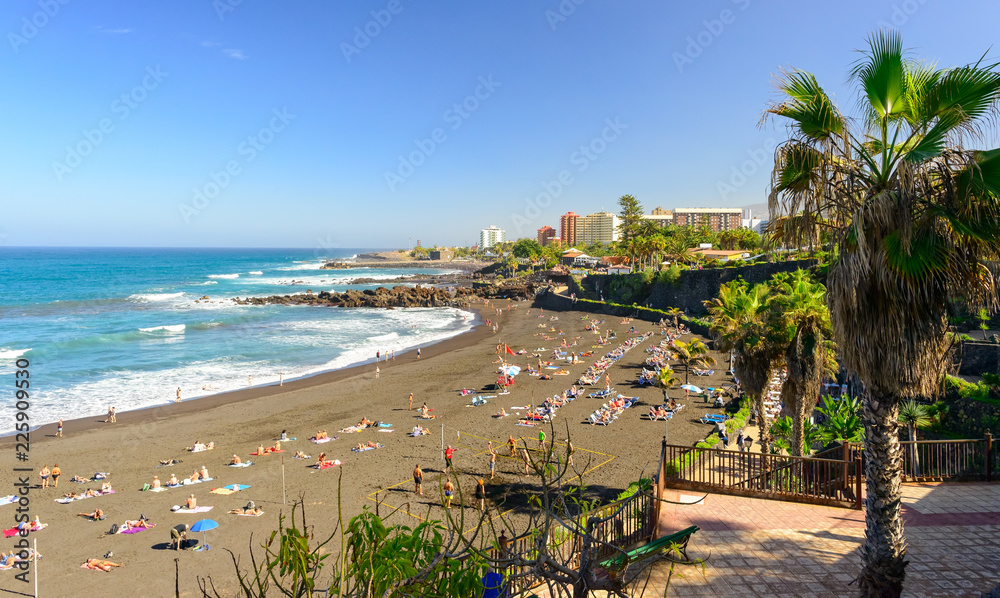Touristen beim Sonnenbaden am Strand von Puerto de la Cruz auf der kanarischen Insel Teneriffa - Spanien