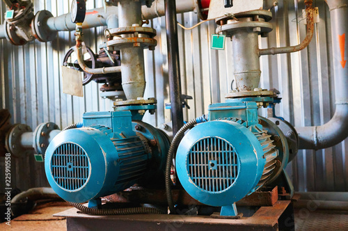 Old blue electric motor with pump, gate valve and pressure gauge on the pipeline.