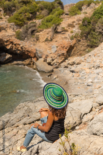 Solo traveller female sitting on the rocks in a beautiful bay