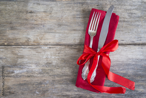 Beautiful vintage fork and knife on red napkin with ribbon on old wooden background wity copy space photo