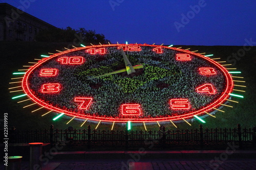 Moscow / Russia - Illuminated clock face red green garden flower watch, evening view of mountain to Park Pobedy (Victory park) at poklonnaya hill in summer evening against dark blue sky  photo