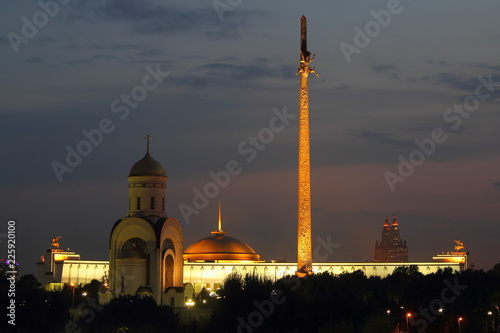 Moscow / Russia - Night view to the Park Pobedy at poklonnaya hill - Victory park, church, stele and monument museum in summer against silhouette trees and dark blue sky with clouds