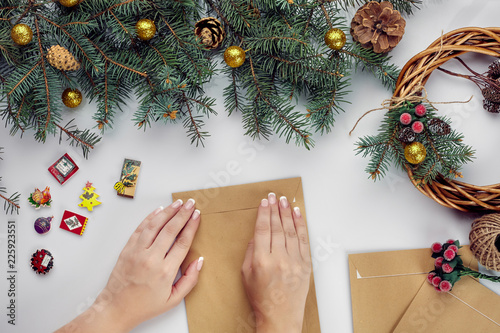 Female hands hold Merry Christmas card and envelope. Christmas decoration background. Flat lay, top view. photo