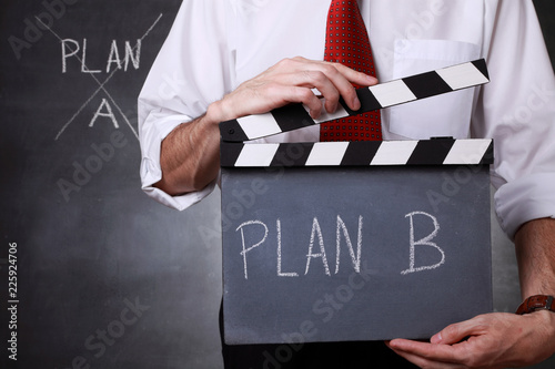 Businessman holding a clapper and ready to start with plan B photo