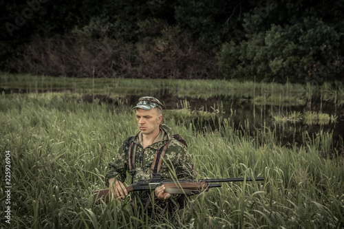 Hunting hunter brutal man breaking through swamp tall grass during hunting season