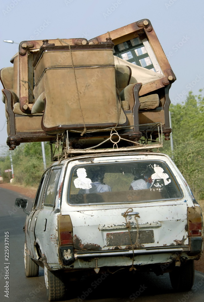 Vieille voiture et son énorme chargement improbable de fauteuils sur une route du Mali, Afrique