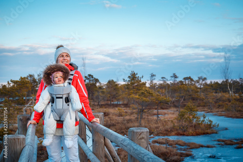Young mother with her little daughter in a baby carrier outside walking on trail in swamp, Kemeri national park, Latvia photo