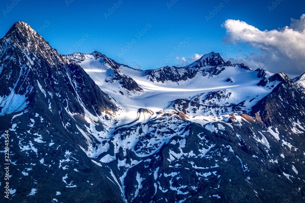 ośnieżone  szczyty Alp austriackich,  częściowo oświetlone - obrazy, fototapety, plakaty 