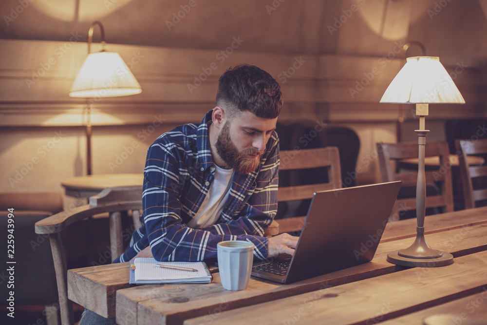 Young professional surfing the Internet on his laptop in a cafe Young professional surfing the Internet on his laptop in a cafe