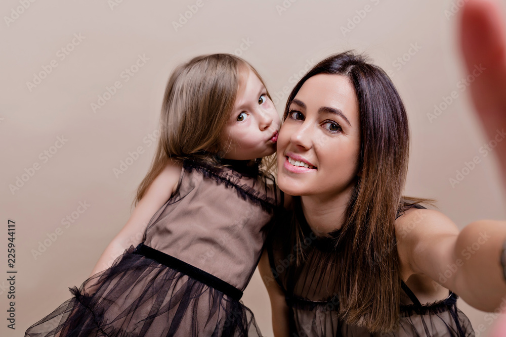 Young beautiful woman with her adorable daughter making selfie with happy smiles on isolated background Young beautiful woman with her adorable daughter making selfie with happy smiles on isolated background