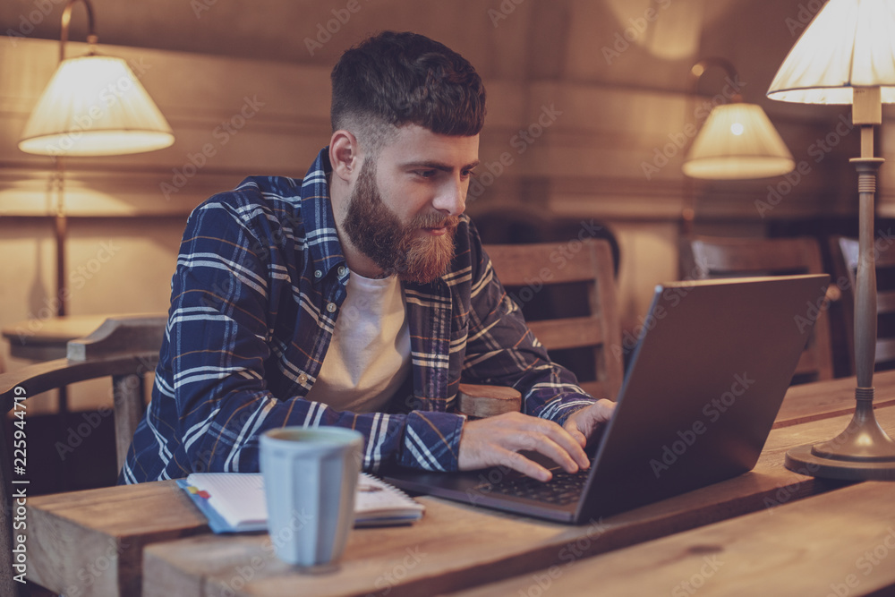 Young professional surfing the Internet on his laptop in a cafe Young professional surfing the Internet on his laptop in a cafe
