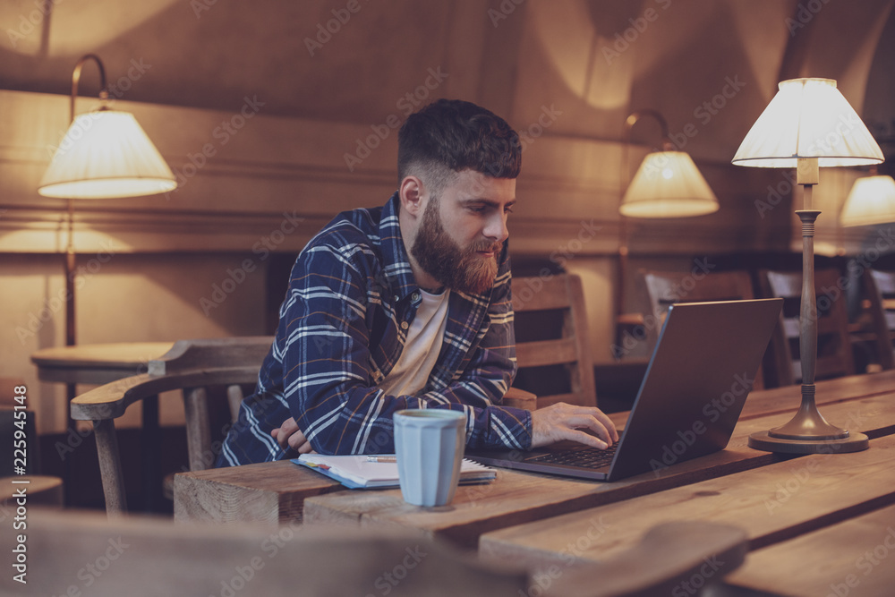 Young professional surfing the Internet on his laptop in a cafe Young professional surfing the Internet on his laptop in a cafe