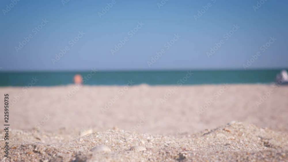close-up glass with drinking water standing in the sand on the beach. The girl taking a glass and siping a water close-up glass with drinking water standing in the sand on the beach. The girl taking a glass and siping a water