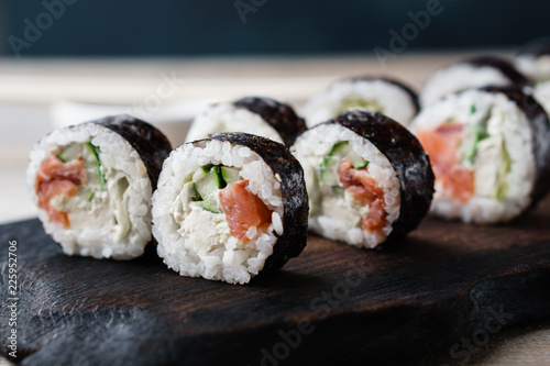 Sushi rolls set on black wooden tray, close up. Asian restaurant menu, food  photo art. Traditional Japanese cuisine