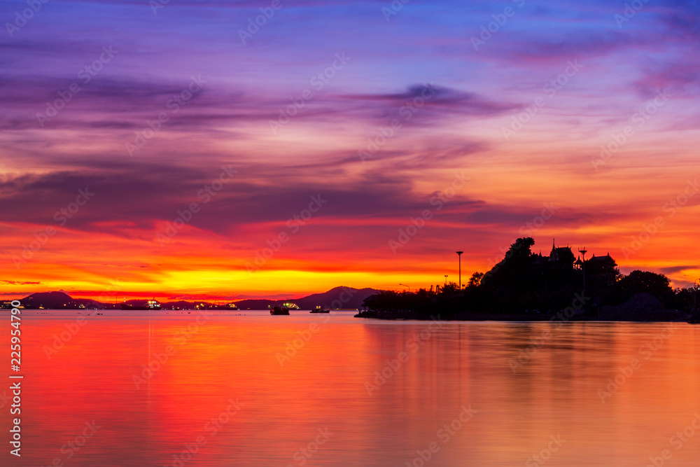 Sun setting in between silhouette mountain range and islands, Thailand famous place called Koh-Loy at Chonburi, shot taken by using long exposure technic therefore smooth water surface like mirror
