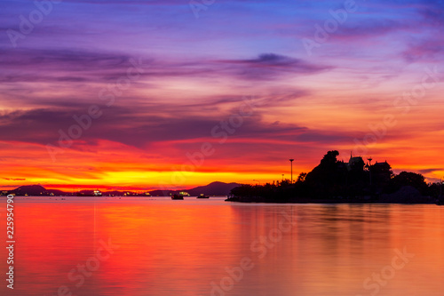 Sun setting in between silhouette mountain range and islands, Thailand famous place called Koh-Loy at Chonburi, shot taken by using long exposure technic therefore smooth water surface like mirror