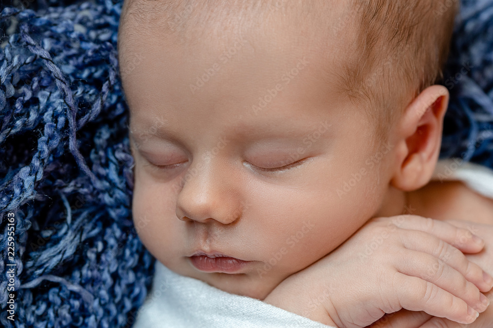 Newborn baby, face closeup. The sleeping Newborn boy under a white