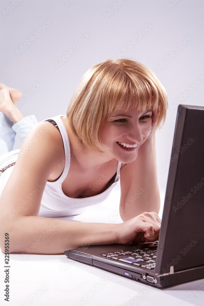 Youth Lifestyle and Technologies Concepts. Excited and Laughing Caucasian Blond Woman With Laptop Against White Backgound on Floor Chatting. Youth Lifestyle and Technologies Concepts. Excited and Laughing Caucasian Blond Woman With Laptop Against White Backgound on Floor Chatting.