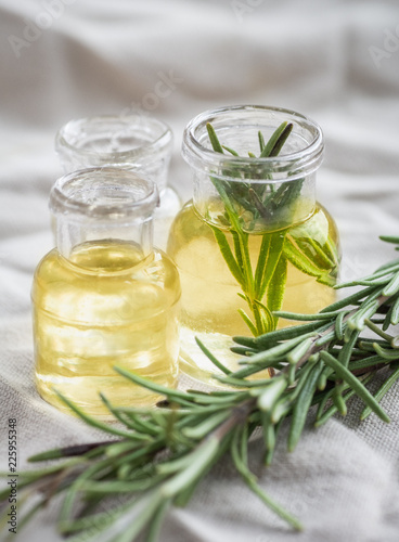 6767961 Rosemary essential oil in small bottles with a fresh rosemary twig closeup