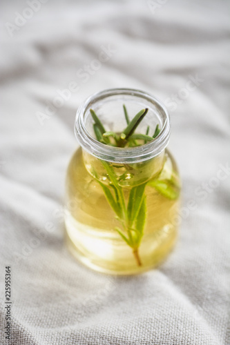 6767963 Rosemary essential oil in small bottle with a fresh rosemary inside closeup