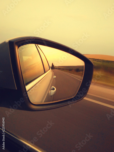 Reflection of sunny road at the car side mirrow. Rear view mirror reflection on sun down