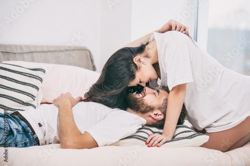 Fotografie Young beautiful and happy couple man and woman at home in bedroom in bed romanti