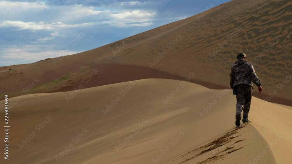 Tourist walking along the edge of the sand dune. Large barkhan in Mongolia sandy dune desert Mongol Els Tourist walking along the edge of the sand dune. Large barkhan in Mongolia sandy dune desert Mongol Els