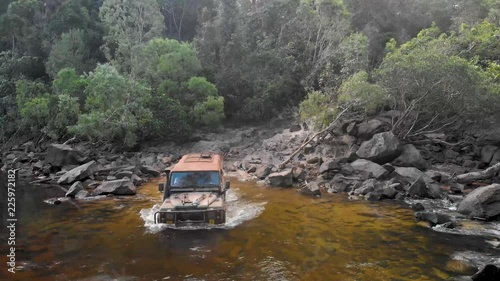 Aerial drone shot following a army land rover, driving through a river crossing, in Cape york, Queensland, Australia photo