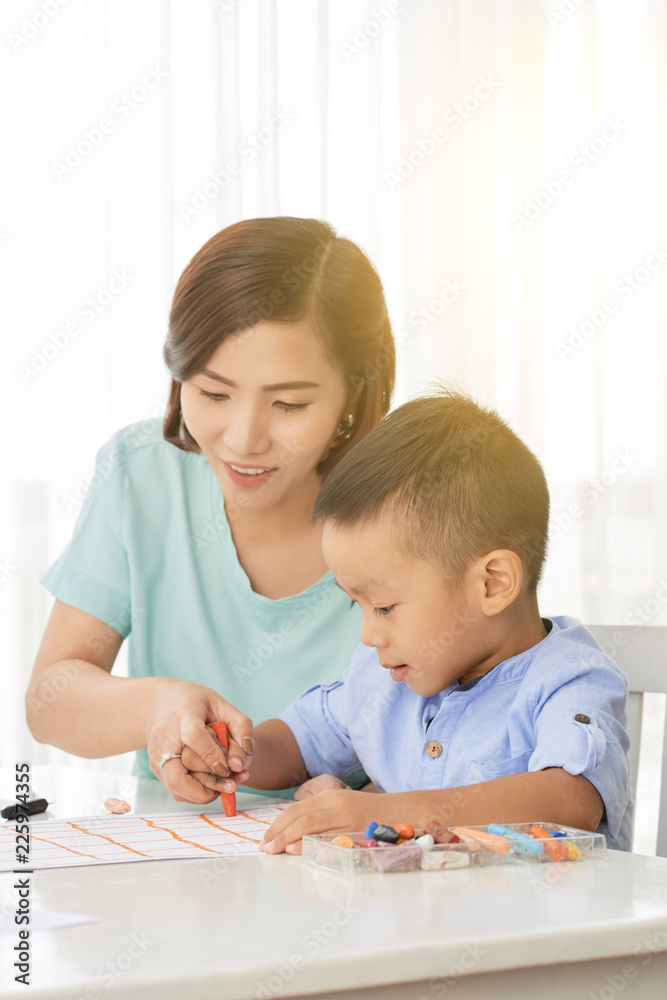 Young teacher helping little boy with drawing