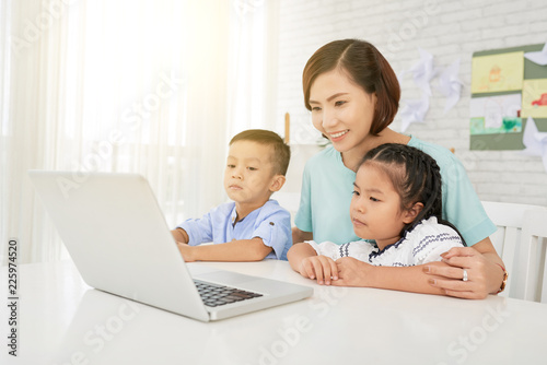 Mother and children watching educational video on laptop at home