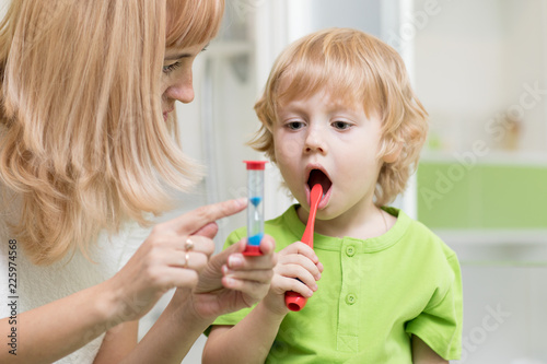 Mother teaching and helping child son how to brush his teeth
